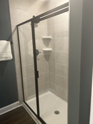 Model Home A sleek shower with glass doors, matte black frame, and elegant gray tile. Perfect for modern living.
