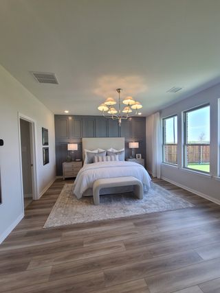 A serene bedroom featuring a soft neutral palette, elegant chandelier, and large windows for natural light.