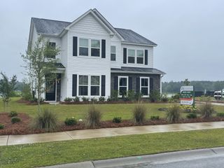 A charming white two-story home with black shutters and landscaped yard in Timothy Lakes by Center Park Homes (Ridgeville, SC).