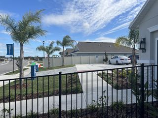 A beautiful community with modern homes, palm trees, and landscaped paths in St. John Preserve by Adams Homes (Palm Bay, FL).