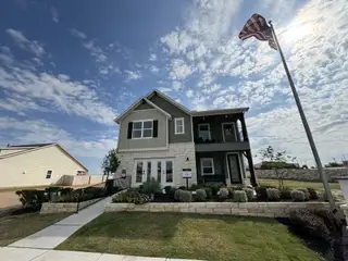 A charming two-story home with a flagpole and landscaped yard in Covered Bridge by Ashton Woods (Hutto, TX).