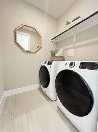 A modern laundry room with sleek appliances, a stylish hexagonal mirror, and ample shelving for storage.