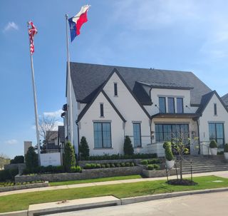 A modern white brick home with manicured landscaping in the Fields community by Huntington Homes (Frisco, TX).