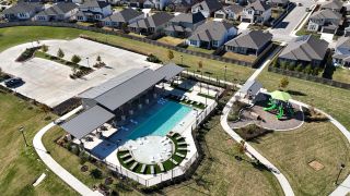 Community Amenities A vibrant community pool and playground in Turner's Village by Meritage Homes, set amidst lush greenery in Buda, TX.