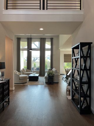 A spacious living area with elegant furniture, large windows, and sleek wooden flooring.