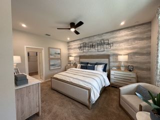 Elegant bedroom with a modern wood accent wall, cozy seating area, and beige tones creating a serene atmosphere.