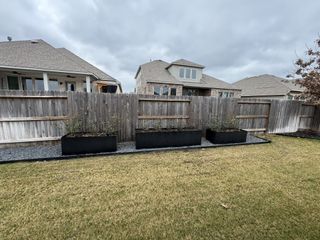 A covered outdoor dining space with a built-in TV, ceiling fan, and grill station in Veramendi by Scott Felder Homes (New Braunfels, TX).