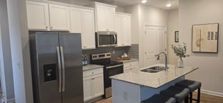 A modern kitchen with white cabinets, stainless steel appliances, and a granite island with seating.