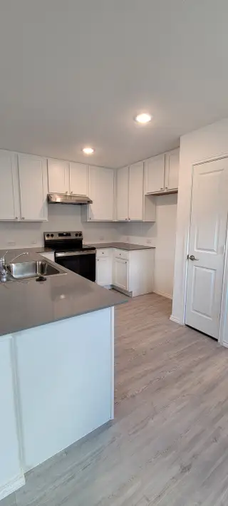 Model Home A sleek modern kitchen with white cabinetry, quartz countertops, and recessed lighting for a bright and open feel.