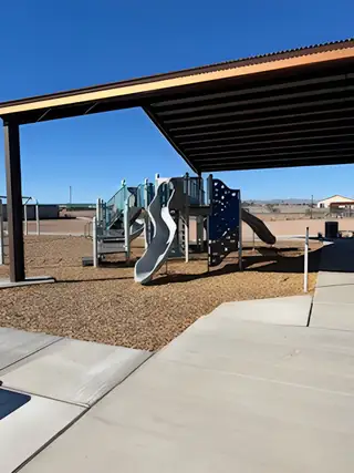 A vibrant playground under a shaded pavilion in North Copper Canyon by Oakwood Homes Co (Surprise, AZ).