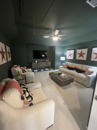 A stylish media room with dark green walls, plush white seating, and star-themed artwork offers a cozy entertainment space.