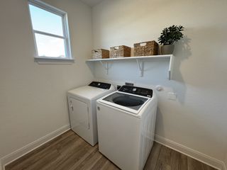A spacious laundry room with a washer, dryer, natural light, and woven storage baskets for a clean and organized feel.