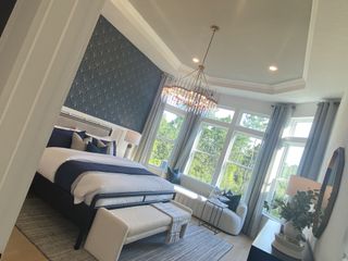 A luxurious bedroom with a bold accent wall, elegant chandelier, and ample natural light from large windows.