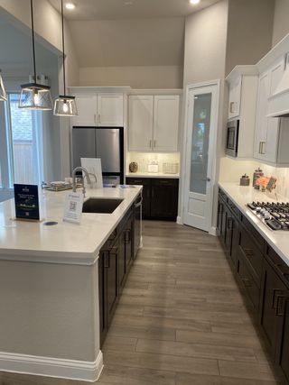 A modern kitchen with sleek two-tone cabinets, stainless steel appliances, and elegant pendant lighting.