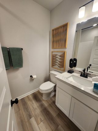 Model Home A modern bathroom with wood flooring, artistic decor, a sleek vanity, and ambient lighting.