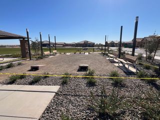 A serene community area with benches and greenery in Sentiero at Windrose by David Weekley Homes (Waddell, AZ).