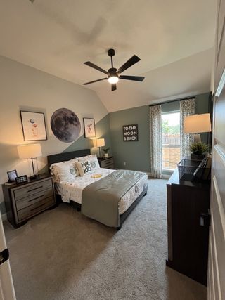 A cozy bedroom with a celestial theme, featuring moon decor, a modern ceiling fan, and elegant drapery.