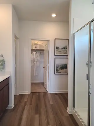 A modern bathroom with wood-style flooring, spacious vanity, and a chic glass shower.
