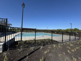 Community Amenities A pristine community pool with a black fence and lush landscaping in Parkside On The River by Perry Homes (Georgetown, TX).