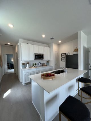 A modern kitchen with sleek white cabinetry, an island, and stylish seating, creating an inviting culinary space.