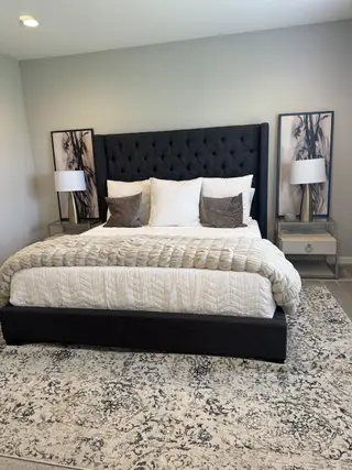 A cozy bedroom featuring a plush tufted headboard, elegant bedding, and sleek nightstands with modern lamps.