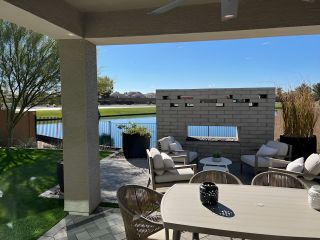 Model Home A cozy outdoor patio with comfortable seating, a modern table, and a serene view of a lake and greenery.