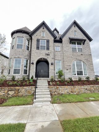 A beautiful brick home with elegant stone accents and landscaping in Edgewater by Grand Homes (Fate, TX).