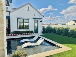 A modern white home with a sleek backyard pool and lush landscaping in Stone Crest by Camelot Homes (Gilbert, AZ).