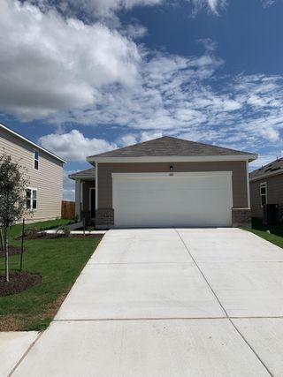 A contemporary beige home with a spacious driveway in Hymeadow by Starlight Homes (Maxwell, TX).