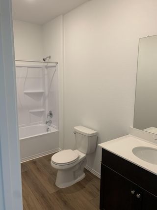 Model Home A modern bathroom featuring a sleek white tub, elegant vanity, and warm wood flooring.