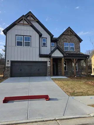 Street view A stunning modern farmhouse with stone and board-and-batten siding in The Paddocks at Doc Hughes by Beazer Homes (Buford, GA).