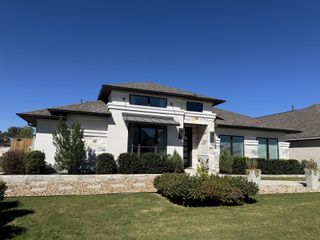Street view A beautiful modern home with a manicured lawn in 6 Creeks by Perry Homes (Kyle, TX).