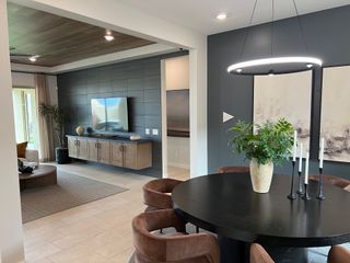 Model Home A modern living space with sleek dark walls, cozy seating, a stylish chandelier, and contemporary decor.