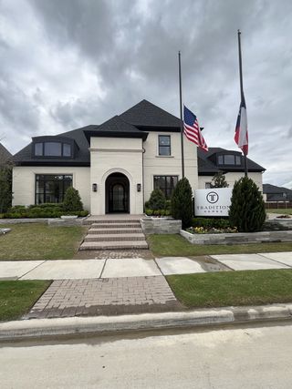 Street view A grand brick home with elegant landscaping in Mustang Lakes by Tradition Homes (Celina, TX).