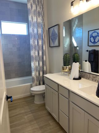 A modern bathroom featuring a sleek vanity, decorative tiles, and contemporary lighting with chic framed artwork.