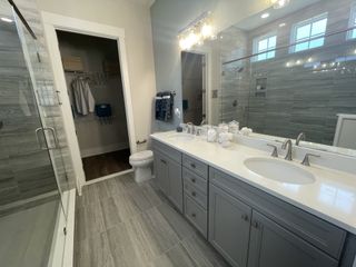 A modern bathroom with a sleek double vanity, spacious shower, and elegant gray tile flooring.