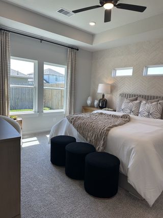 A cozy bedroom with natural light, modern decor, textured wallpaper, and soft carpeting for a comfortable retreat.