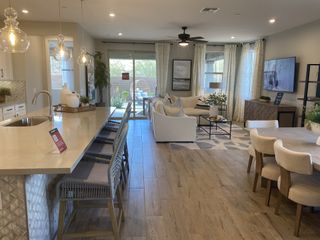 Model Home An open-concept living space features a modern kitchen with a large island, a comfortable living room with a plush sofa, and a dining area with a table set for six.