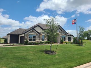 Street view A charming stone-accented home with lush landscaping in Creekview Farms by Altura Homes (Greenville, TX).