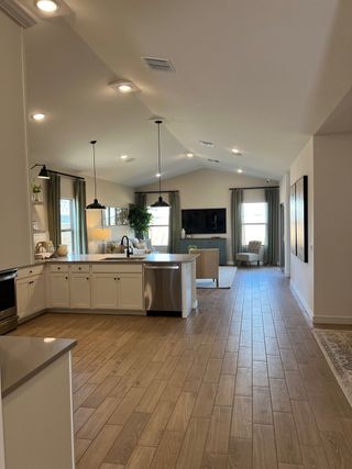 An open-concept living area with sleek wood flooring, modern lighting, and a bright, spacious kitchen.
