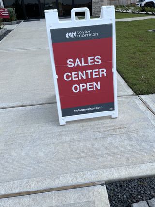 Street view A sales center sign stands welcoming visitors at Redbud 40s by Taylor Morrison in Hockley, TX.