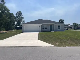 Street view A modern gray home with a spacious driveway in Marion Oaks by Zephyr Homes in Ocala, FL.
