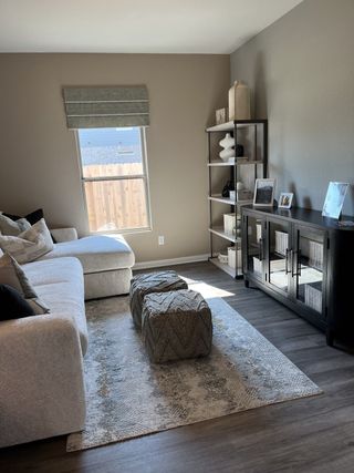 A cozy living room with a plush sectional, decorative ottomans, and a sleek cabinet in neutral tones.