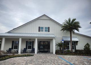 A charming clubhouse with a cozy porch and landscaping in Del Webb Wildlight by Del Webb (Wildlight, FL).