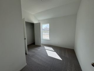 A sunlit room with plush carpeting, neutral walls, and a walk-in closet, perfect for a cozy and inviting atmosphere.