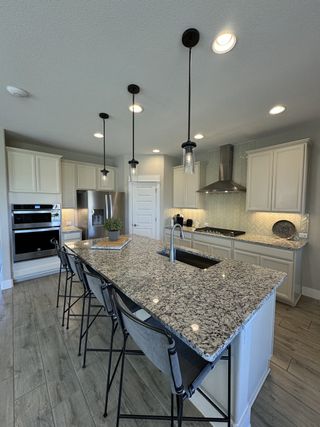 A modern kitchen with a granite island, elegant pendant lighting, and sleek appliances, offering style and functionality.