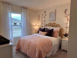 A cozy bedroom with a rattan headboard, floral wall decals, soft pink bedding, and sheer curtains, creating a dreamy atmosphere.