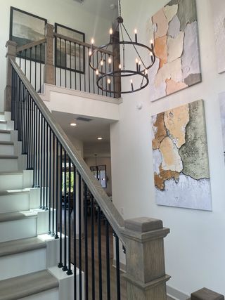 A modern stairway with elegant artwork, sleek black railings, and a chic chandelier.