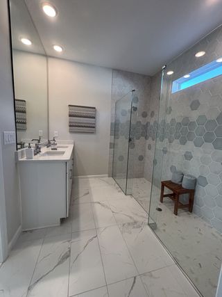 A chic bathroom features hexagonal tiles, marble floors, and a sleek double vanity with modern lighting.