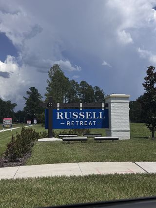 Welcome to Russell Retreat by Lennar in Green Cove Springs, FL. Lush greenery and a striking sign greet visitors.